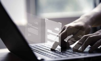 Hand using laptop computer with virtual screen and document for online approve paperless quality assurance and ERP management concept.